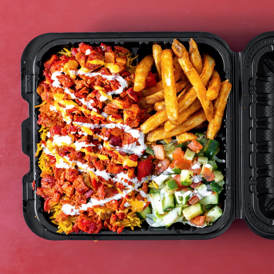Takeout tray filled with seasoned rice, saucy shredded meat, French fries, and cucumber-tomato salad.